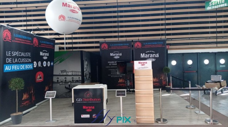 Vue générale du stand de GD Distribution, pour leur présentation d'événement de leur salon professionnel, avant l'arrivée des visiteurs. Stand modulaire, avec plusieurs Roll-up imprimés et un ballon sur mat sphérique personnalisé et imprimé, une sphère de D = 1.5 m monté sur un mat télescopique H = 6 m, pied platine.
