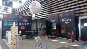 Un exemple concret de stand de salon professionnel, ici un stand modulaire, avec centre un magnifique ballon sur mat sphérique et imprimé du logo de l'entreprise.