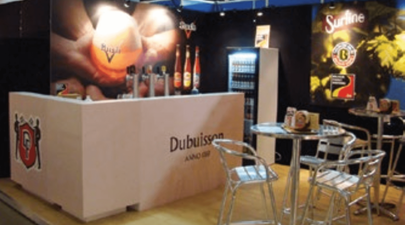 DUBUISSON : un stand de salon professionnel, de type modulaire, avec un comptoir bar à boisson, tables et chaises, fond PVL imprimé personnalisé.